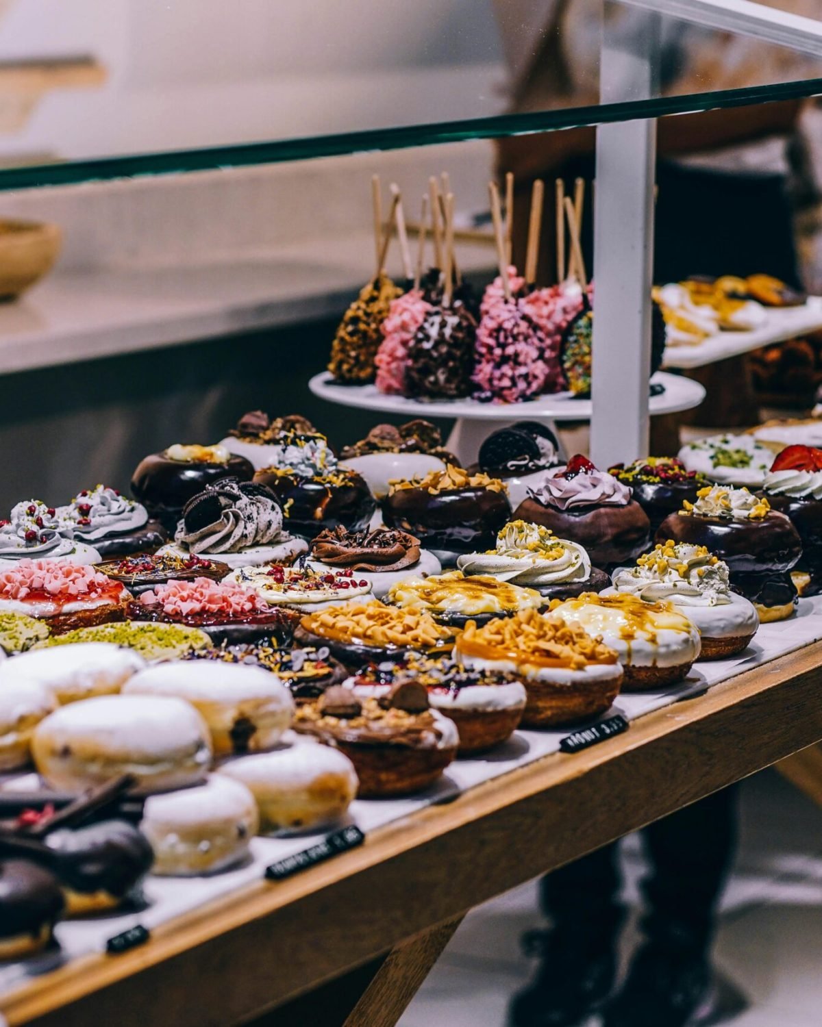 A tempting display of various donuts and pastries in a bakery. Ideal for food lovers and culinary enthusiasts.